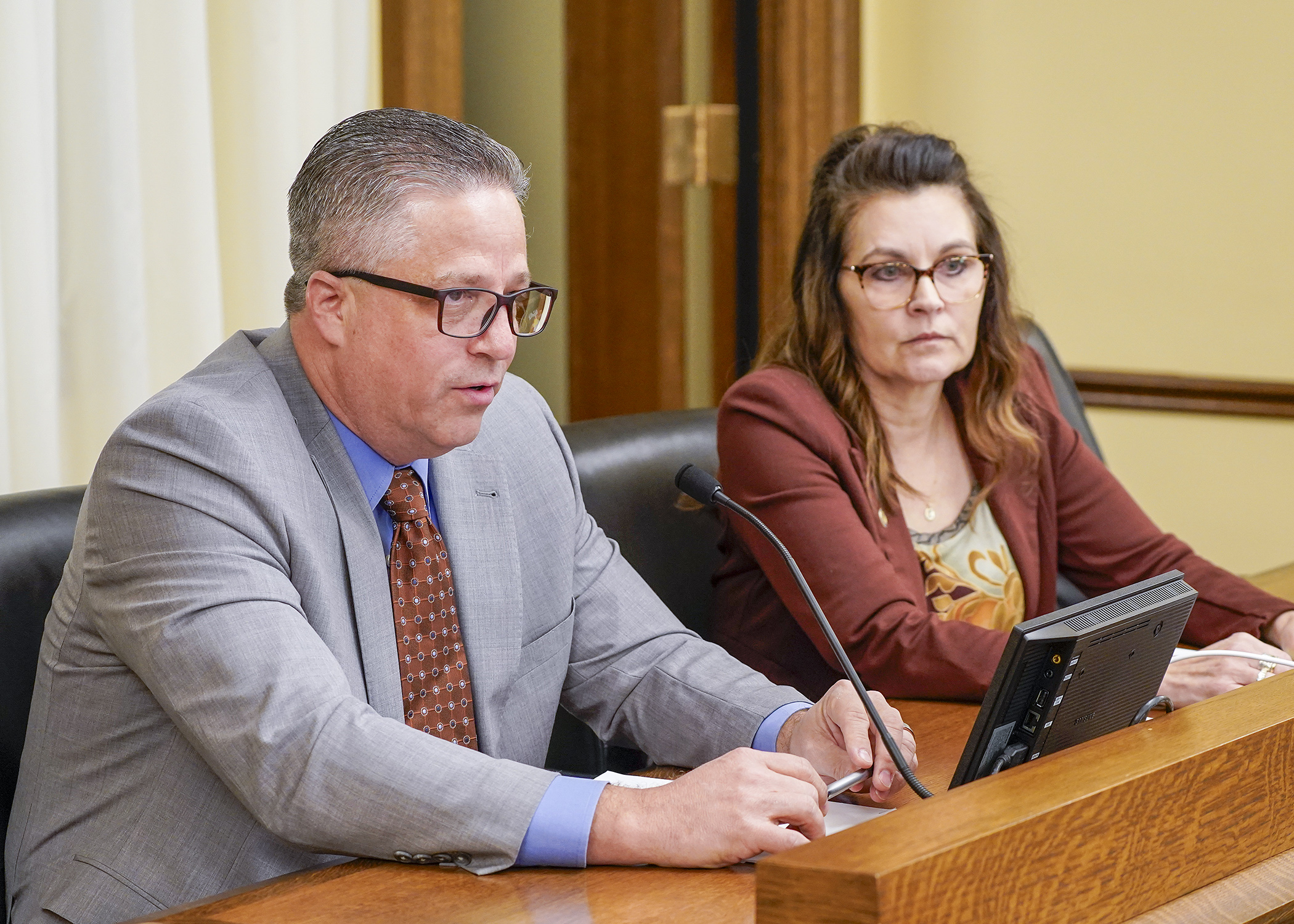 Paxton Whiffler, chief operating officer for Monarch Healthcare Management, testifies before the House Human Services Finance and Policy Committee Feb. 27 in support of a bill sponsored by Rep. Natalie Zeleznikar, right, to repeal the Nursing Home Workforce Standards Board. (Photo by Andrew VonBank)